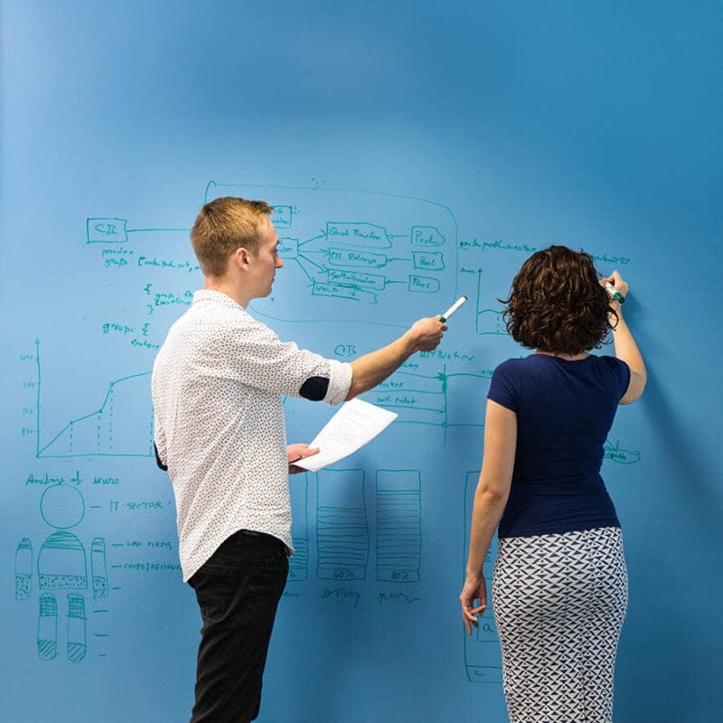Personas escribiendo en una pared azul pintada conpintura pizarra transparente