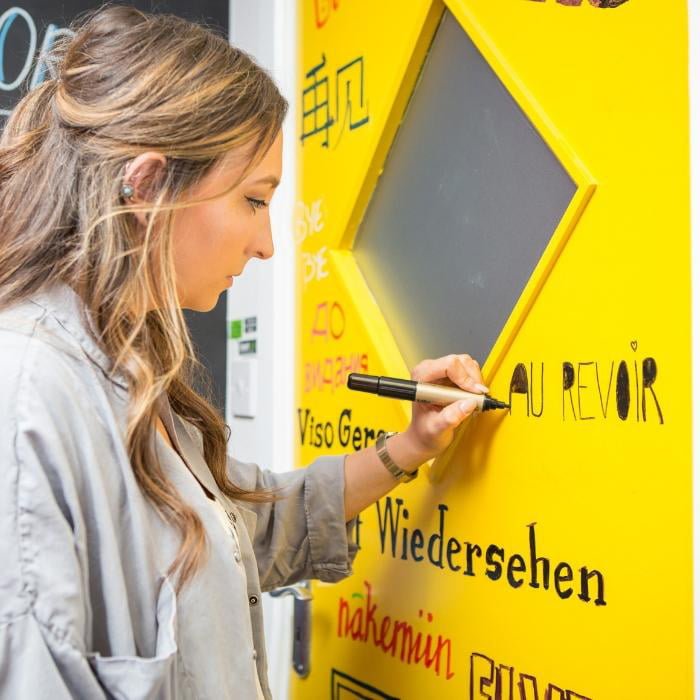 Escribiendo en una puerta amarilla pintada con Smart Pintura Pizarra Transparente.