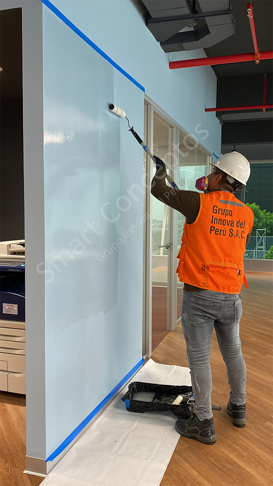 un maestro preparando una pared para aplicar pintura pizarra transparente en una pared azul